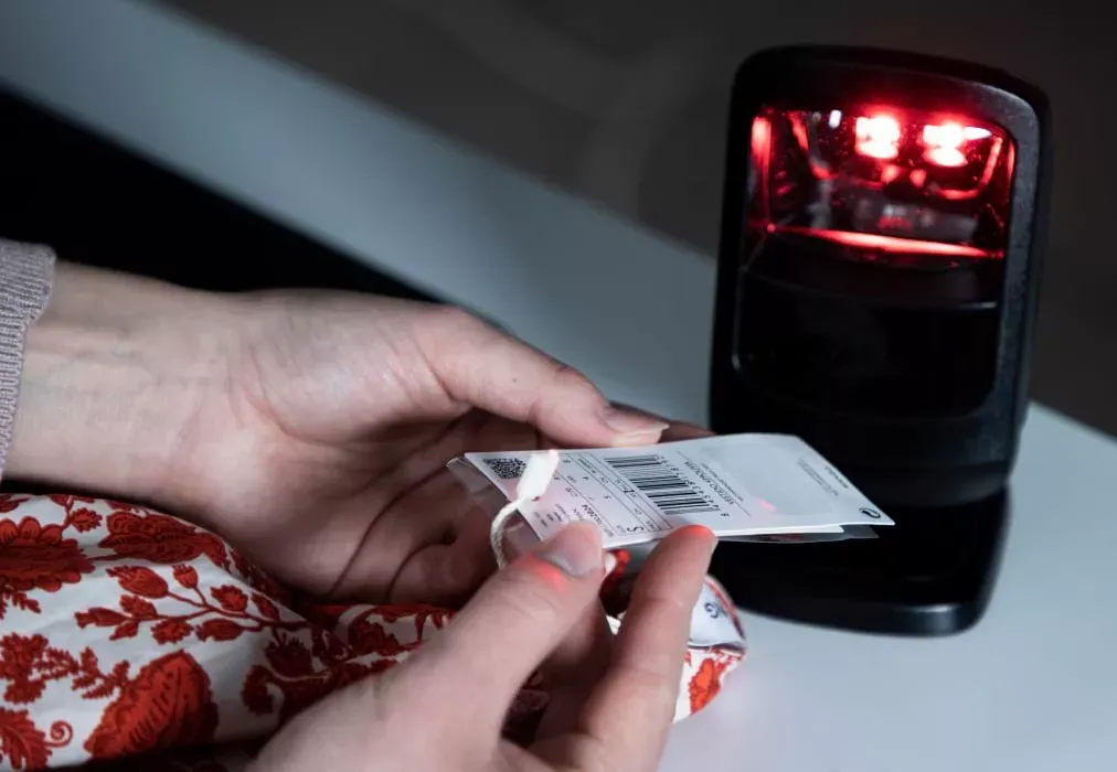 Close das mãos escaneando a etiqueta de código de barras da roupa para inventário