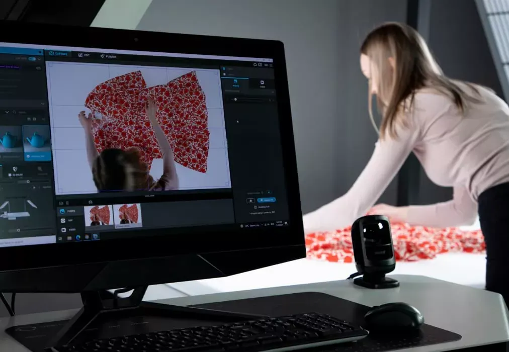Fotógrafo ajustando peça de roupa floral com visualização ao vivo no monitor