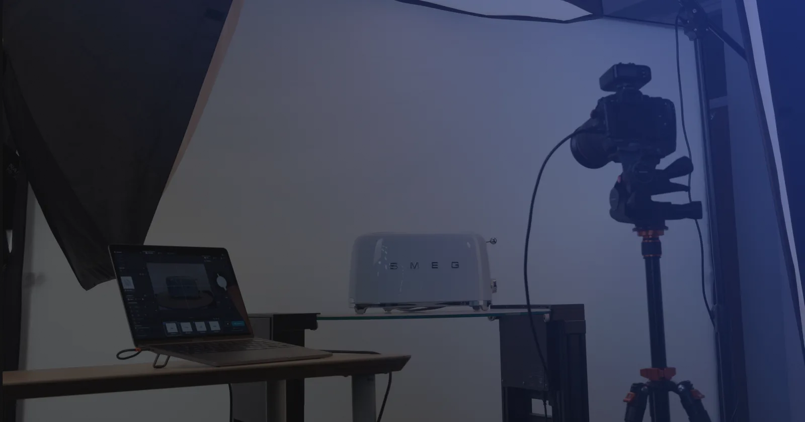 Set de fotografia de produto com tethering: um notebook com o software de captura ao lado de uma câmera no tripé e um produto sobre uma prateleira de vidro