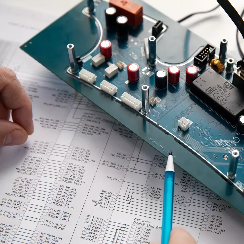 Engenheiro analisando placa de circuito eletrônico e diagrama esquemático